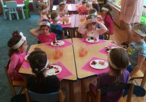 Dzieci siedzą przy stolikach degustują pokarmy w kolorze różowym i fioletowym.